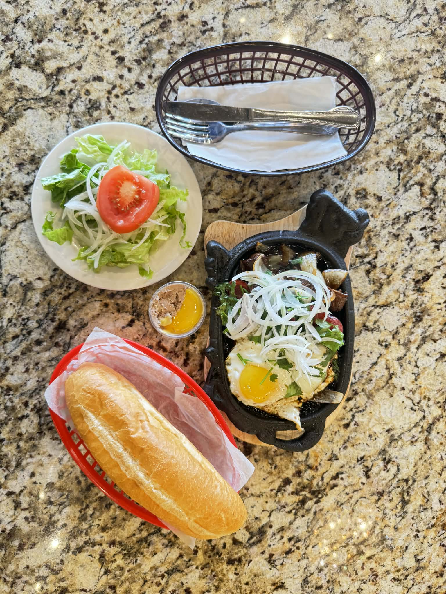 Sizzling cast-iron plate of bò né with steak, egg, and pâté